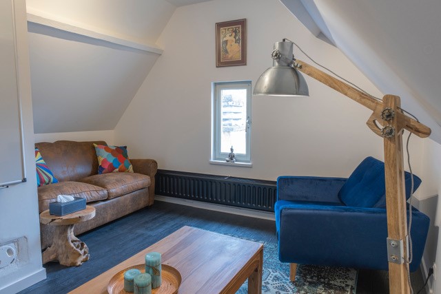 Cabinet de consultation à louer pour thérapeuteavec canapé en cuir, fauteuil bleu, table basse en bois
